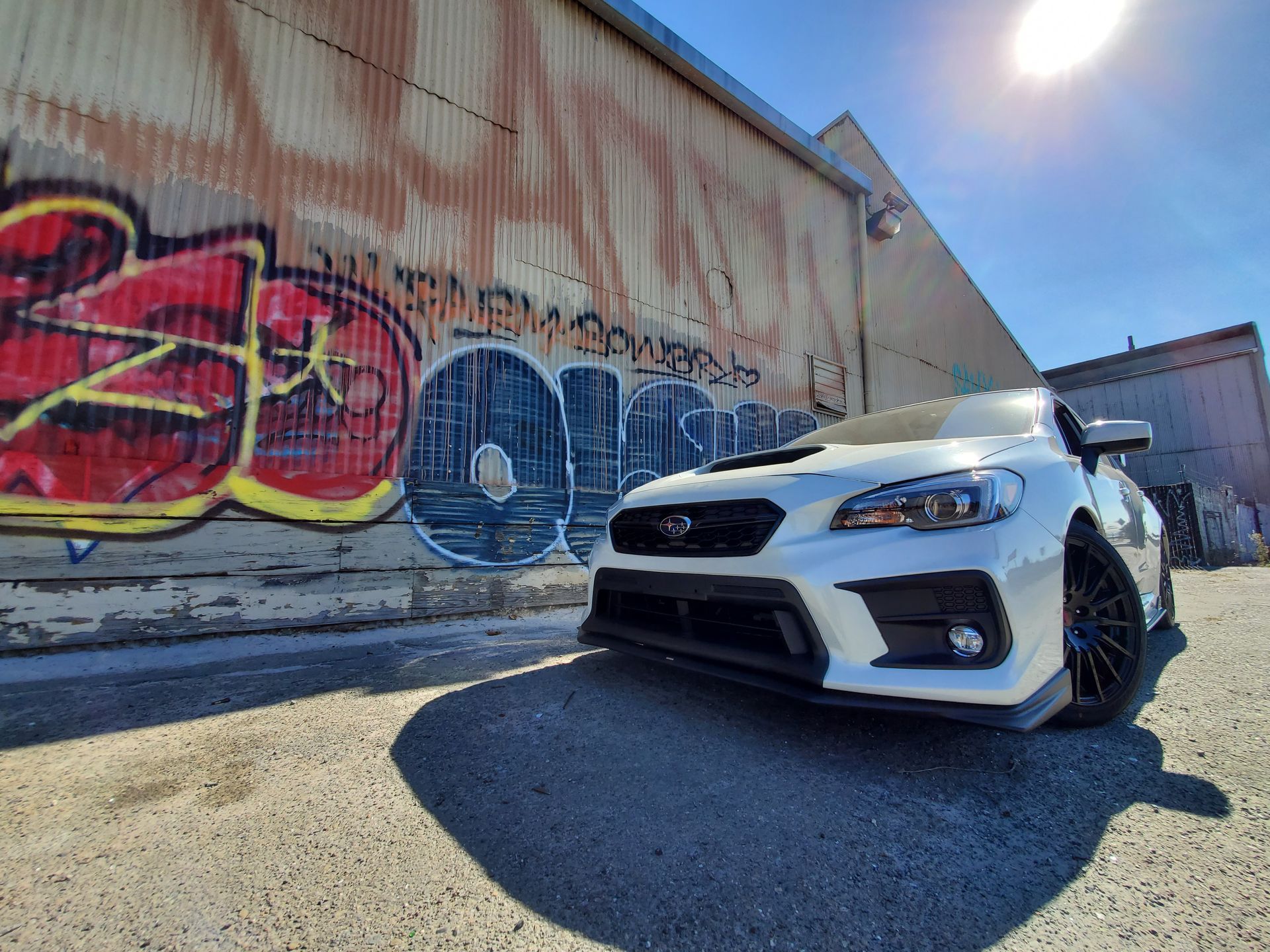 A white car is parked in front of a building with graffiti on it | Griffin Motorwerke