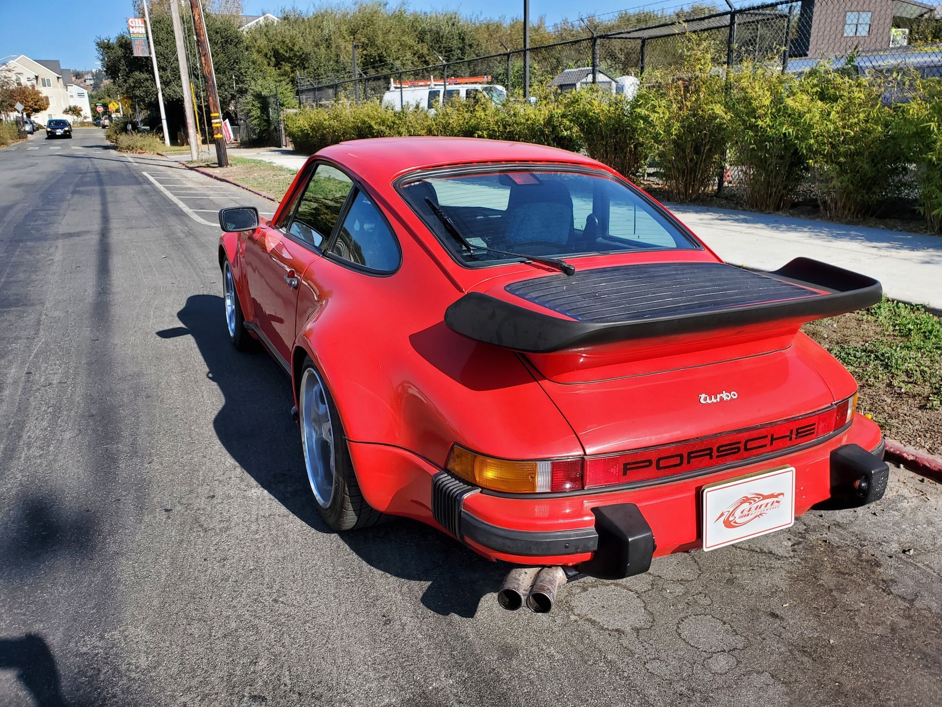 A red porsche 911 turbo is parked on the side of the roadv
