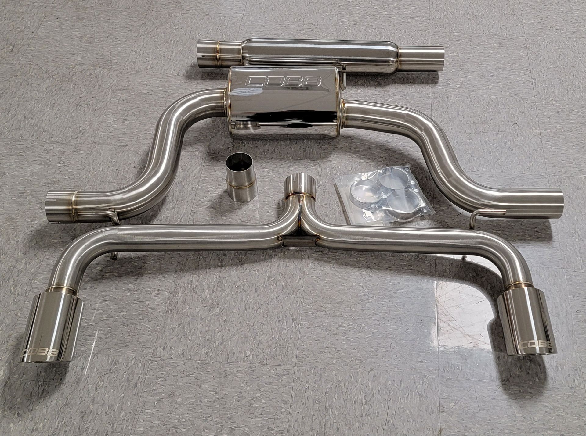 A stainless steel exhaust system is sitting on a marble floor | Griffin Motorwerke