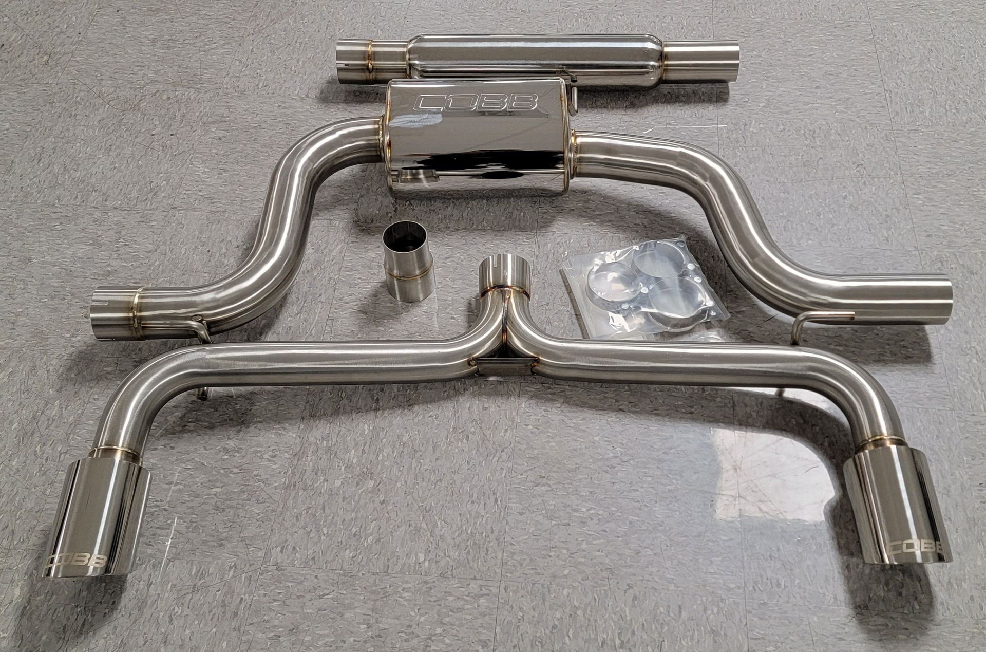 A stainless steel exhaust system is sitting on a concrete floor | Griffin Motorwerke
