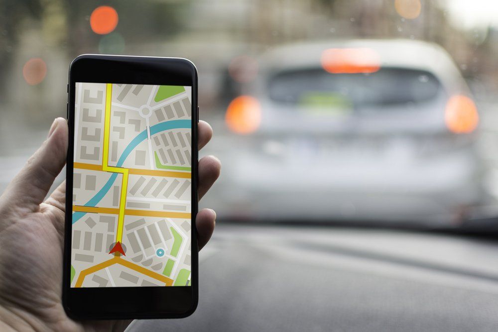 Person holding a phone tracking another car on a map