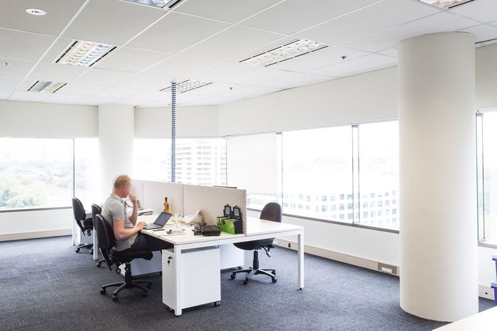 Two people are working in an office with a sign that says affordable fitouts and stripouts