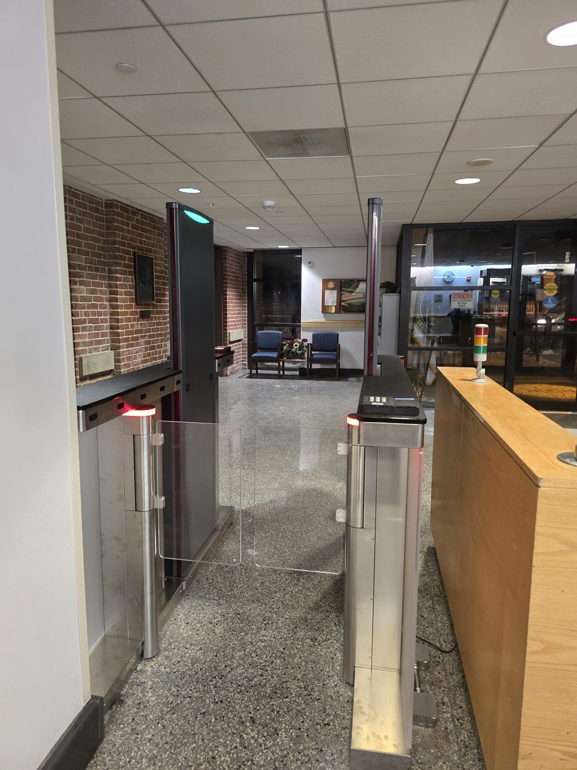 Turnstiles at an entrance. The left turnstile is open, the right is closed. A counter and door are visible.