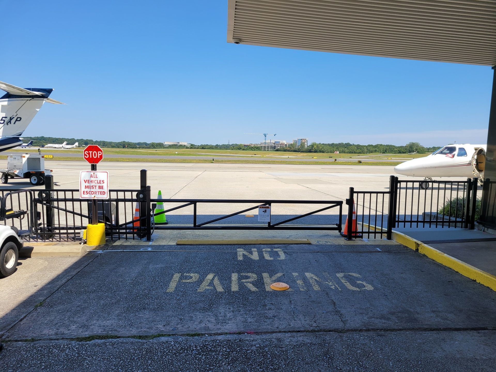 Black gate at airport, leading to the runway. 
