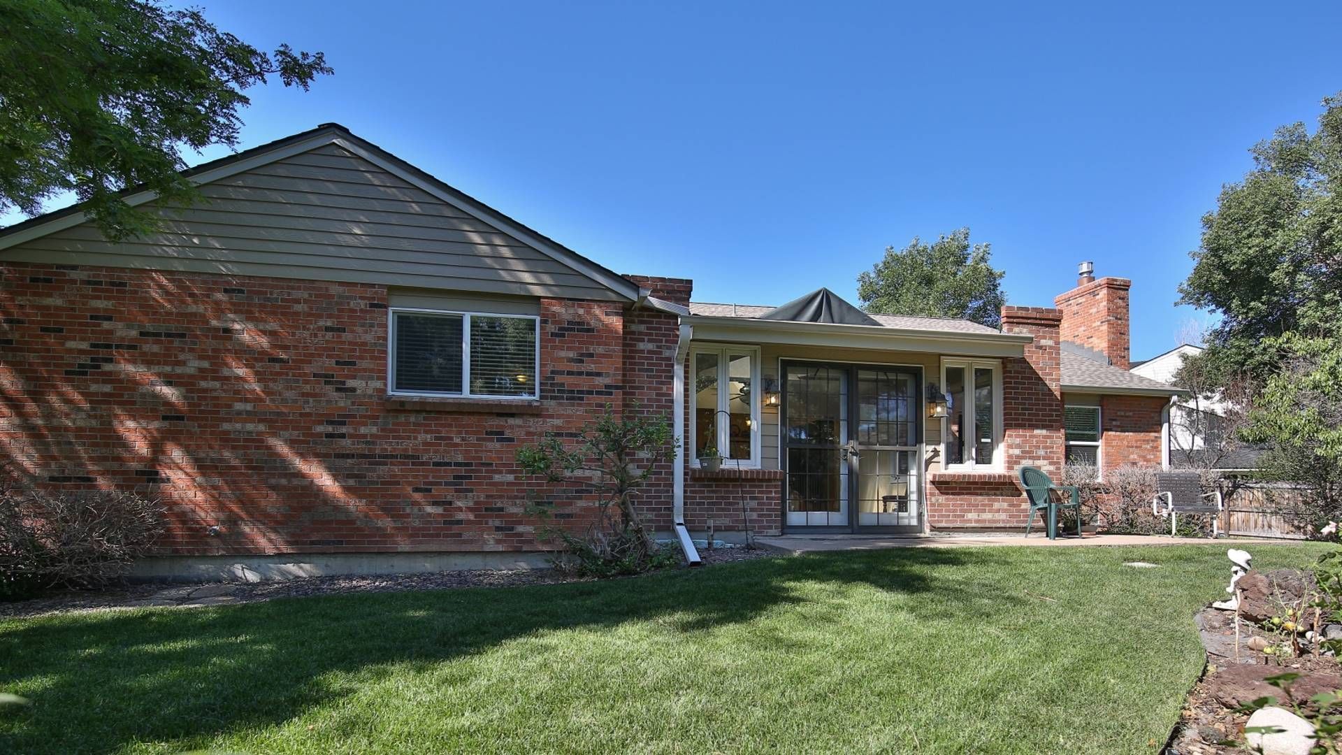 Brick house with green lawn under a clear blue sky.