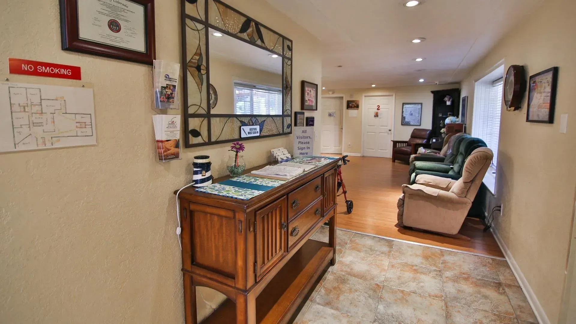 Hallway with wooden furniture, mirror, and seating; light-colored walls; tile and wood floors; and a 