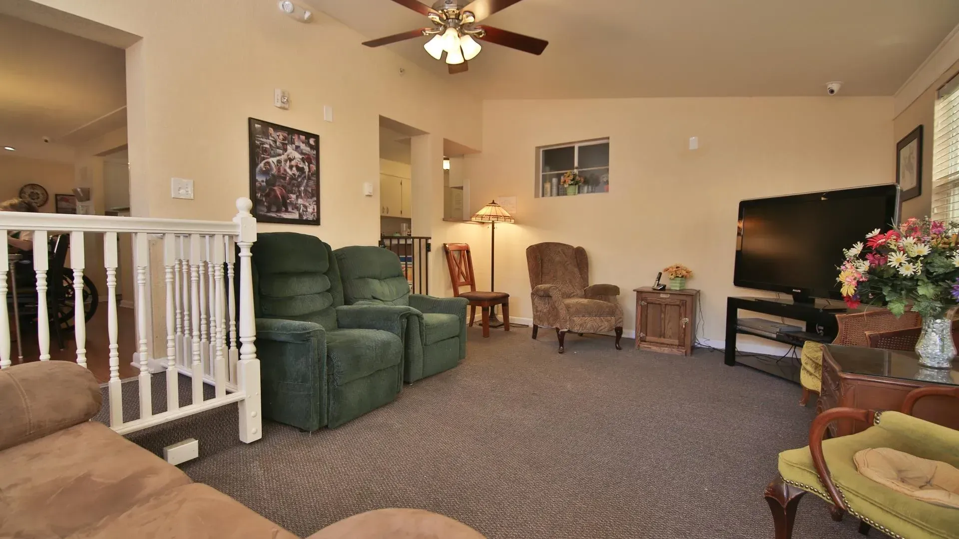 Living room with green recliners, a TV, and floral arrangement.