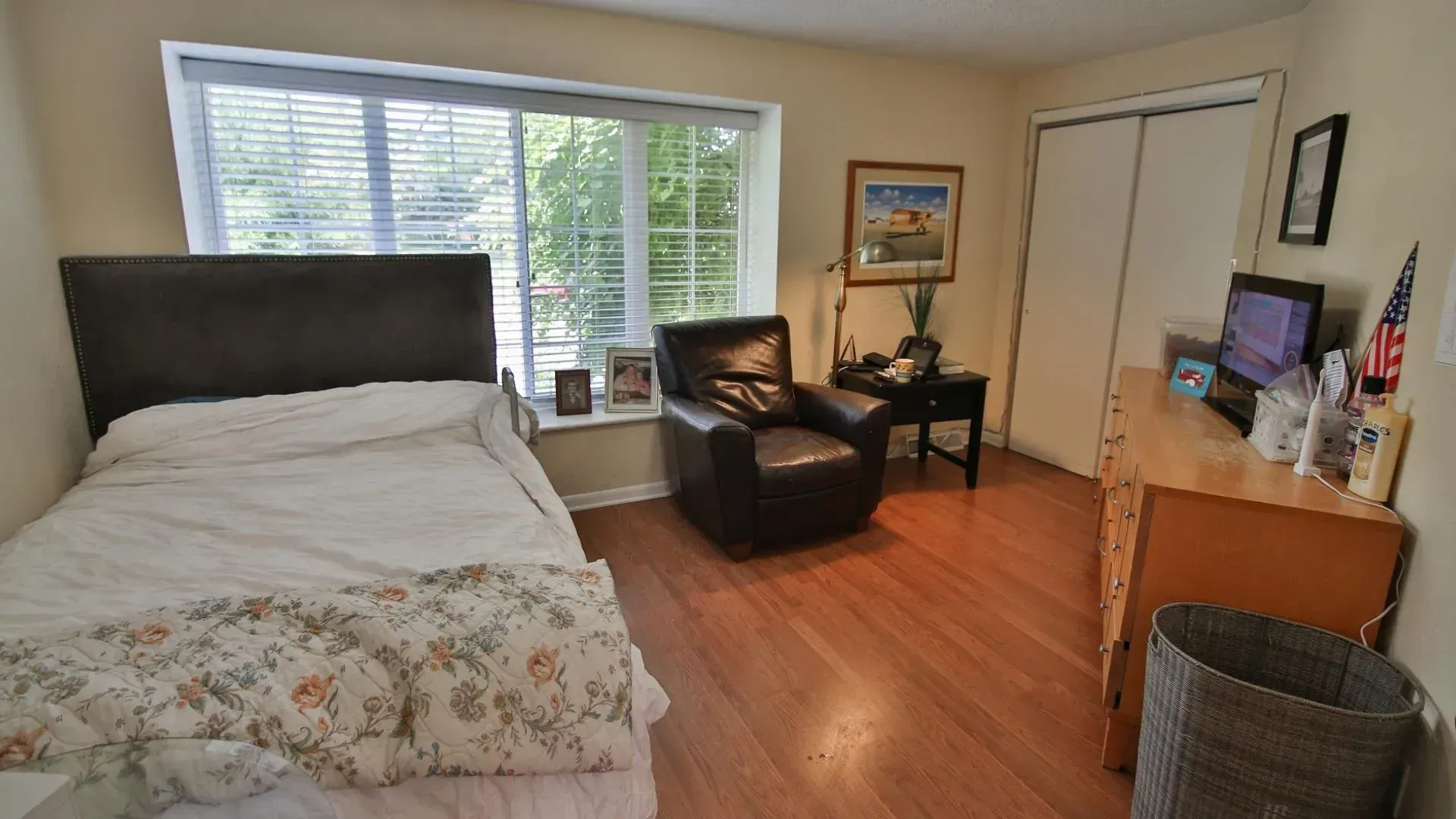Bedroom with bed, armchair, desk, and window.