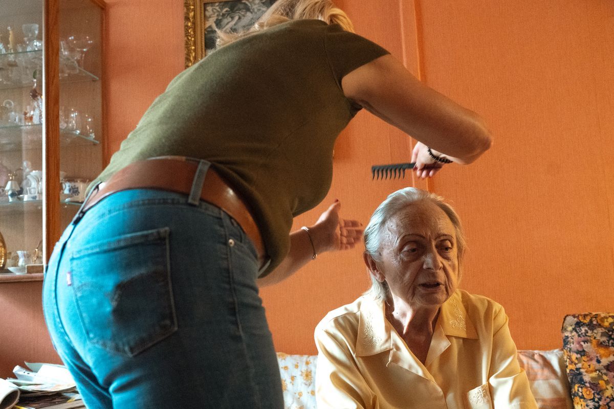 Caregiver helping an older woman with grooming in a comfortable home