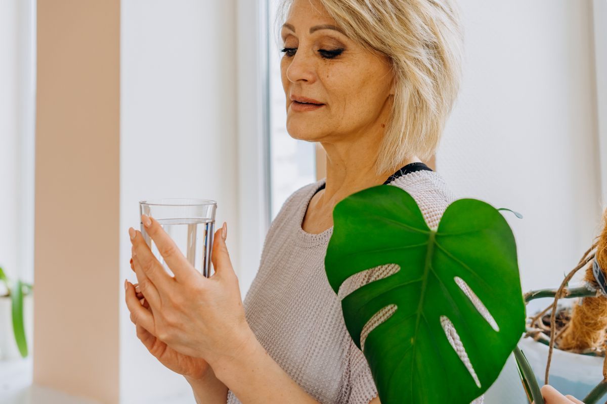 Senior woman holding a glass of water to support healthy hydration