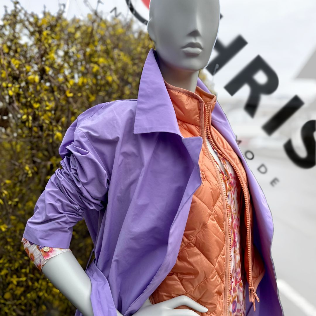 Eine Schaufensterpuppe trägt eine lila Jacke und eine orange Weste