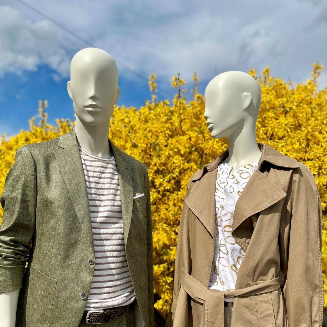 Zwei Schaufensterpuppen stehen vor einem Feld mit gelben Blumen