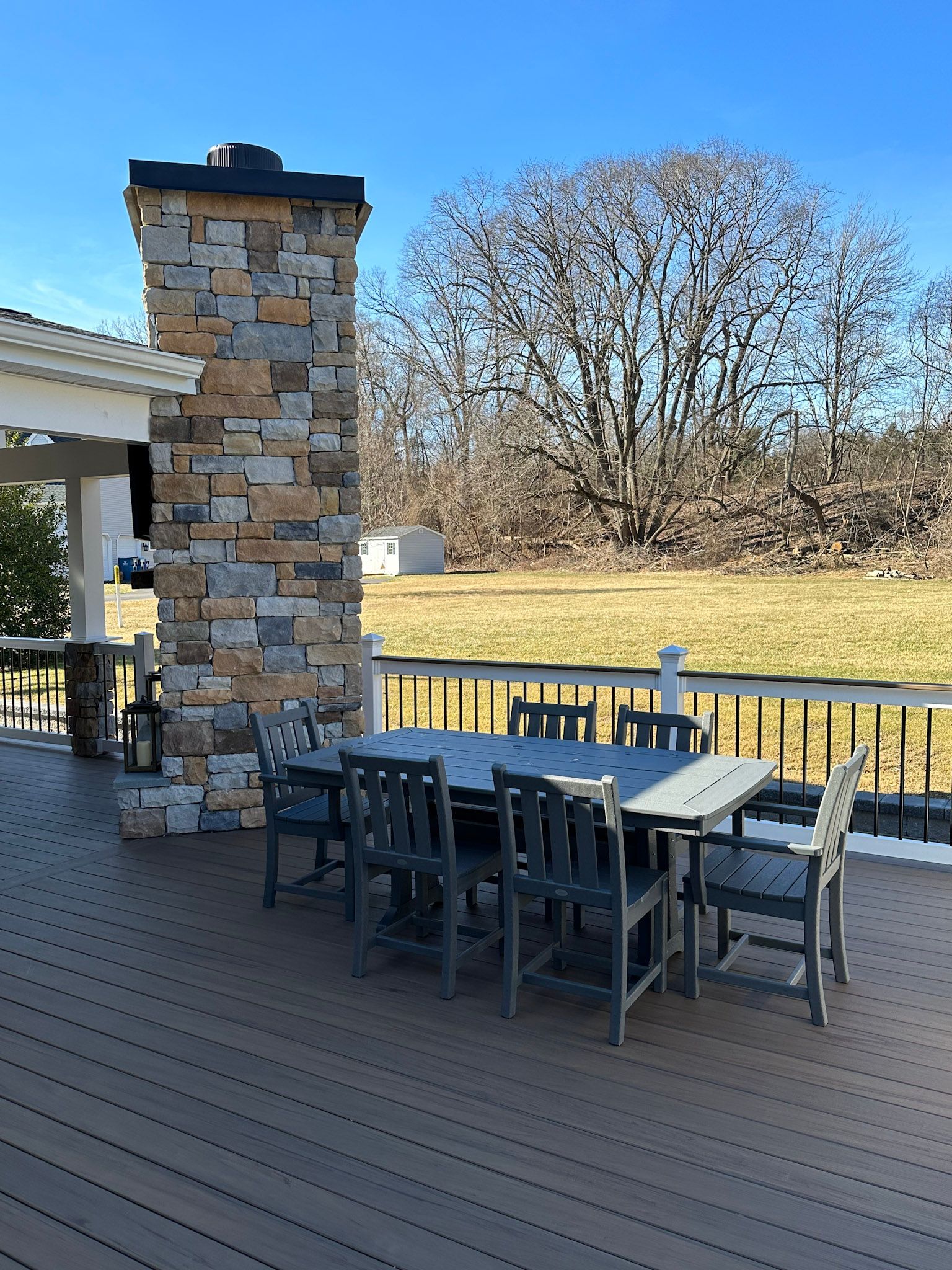 a deck with a table and chairs and a stone chimney