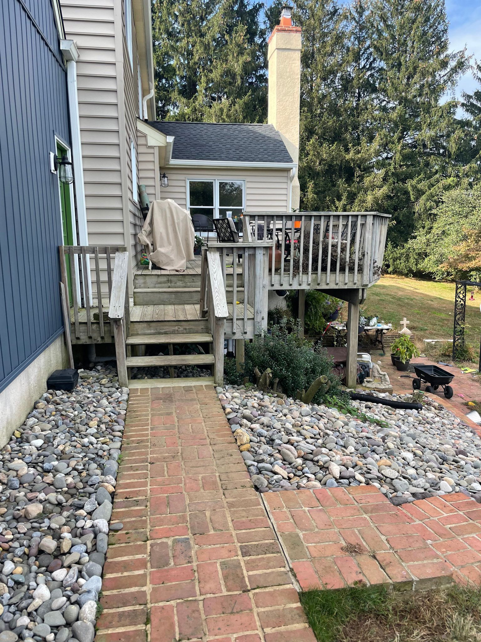 a brick walkway leading to a house with a deck and stairs .