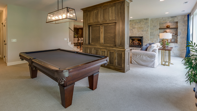 a pool table is sitting in a living room next to a fireplace .