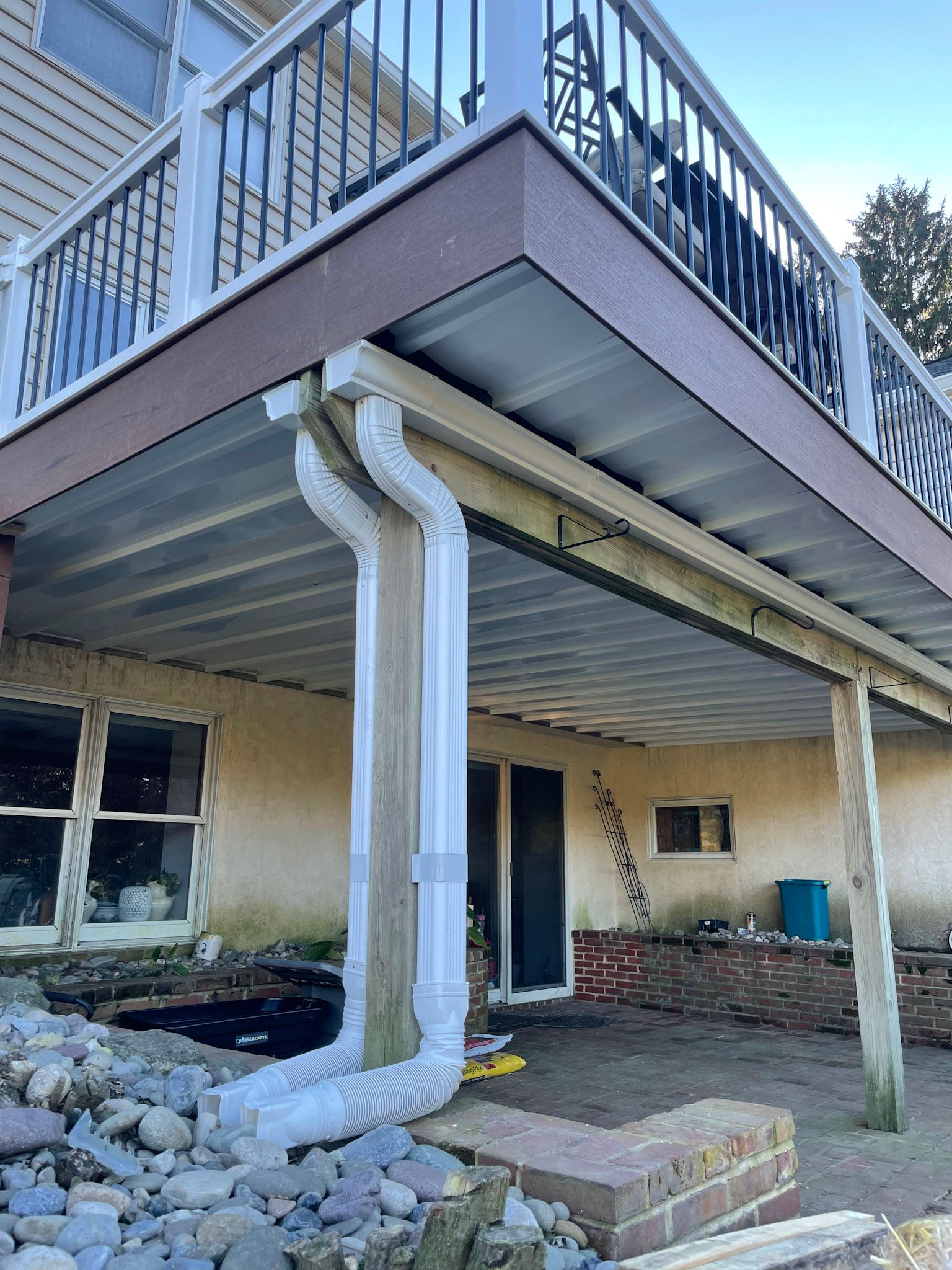a large deck with a railing is sitting underneath a house .
