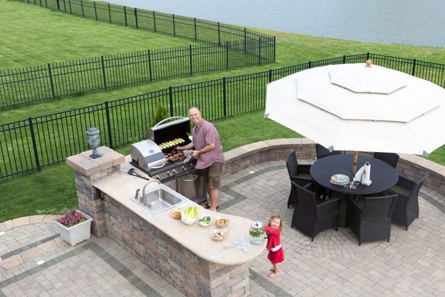 a man is grilling food on a patio next to a table and chairs .