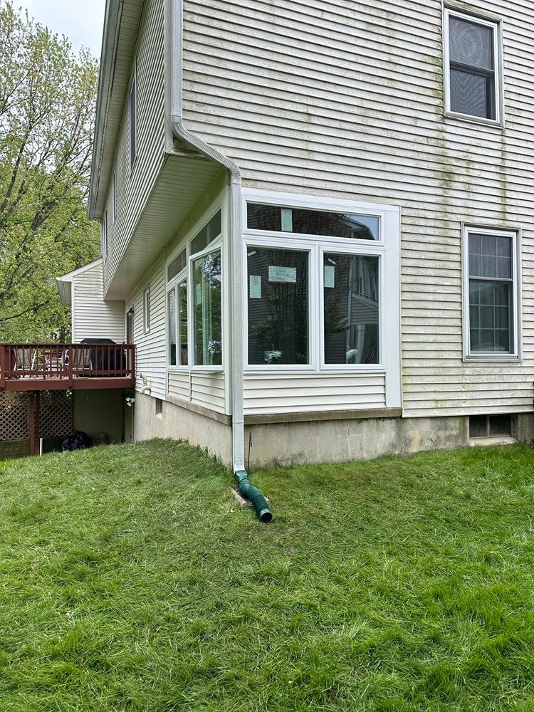 a house with a lot of windows is sitting on top of a lush green lawn .