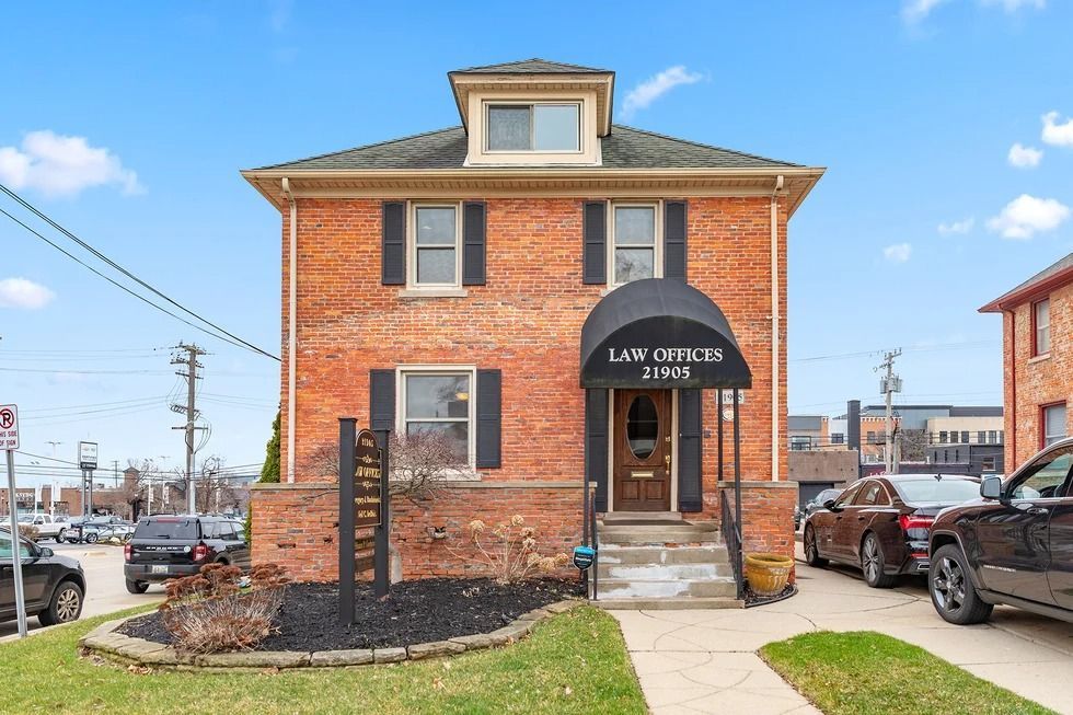 A brick house with cars parked in front of it.