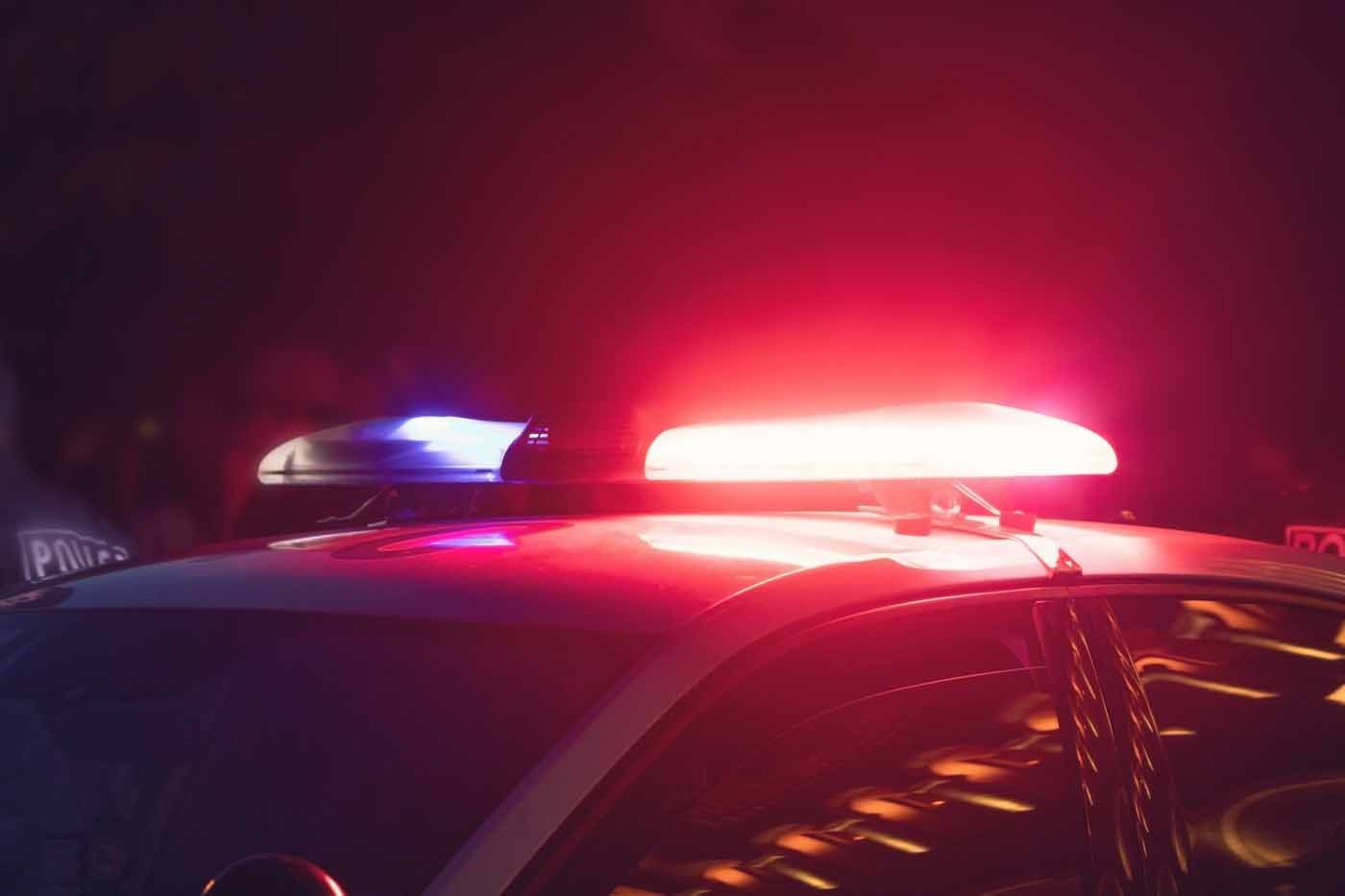 A police car with red and blue lights on top of it at night.