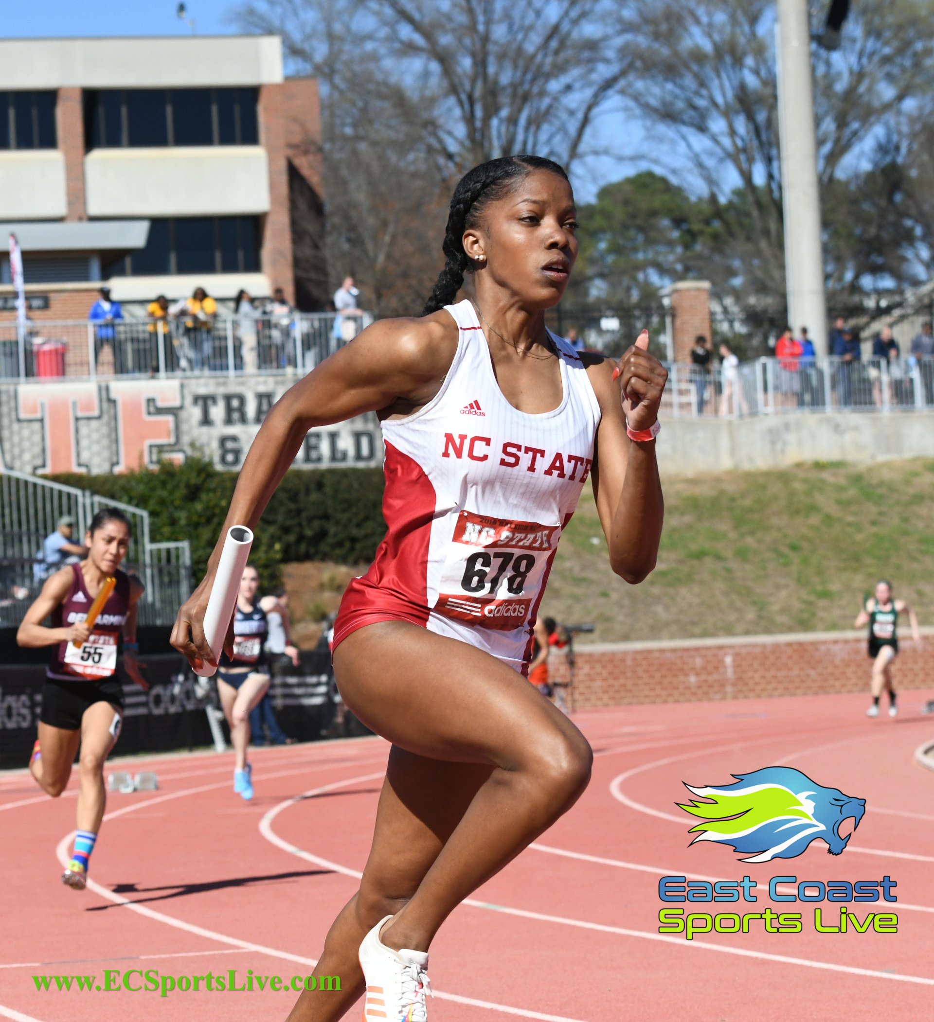 A woman wearing a nc state jersey is running on a track
