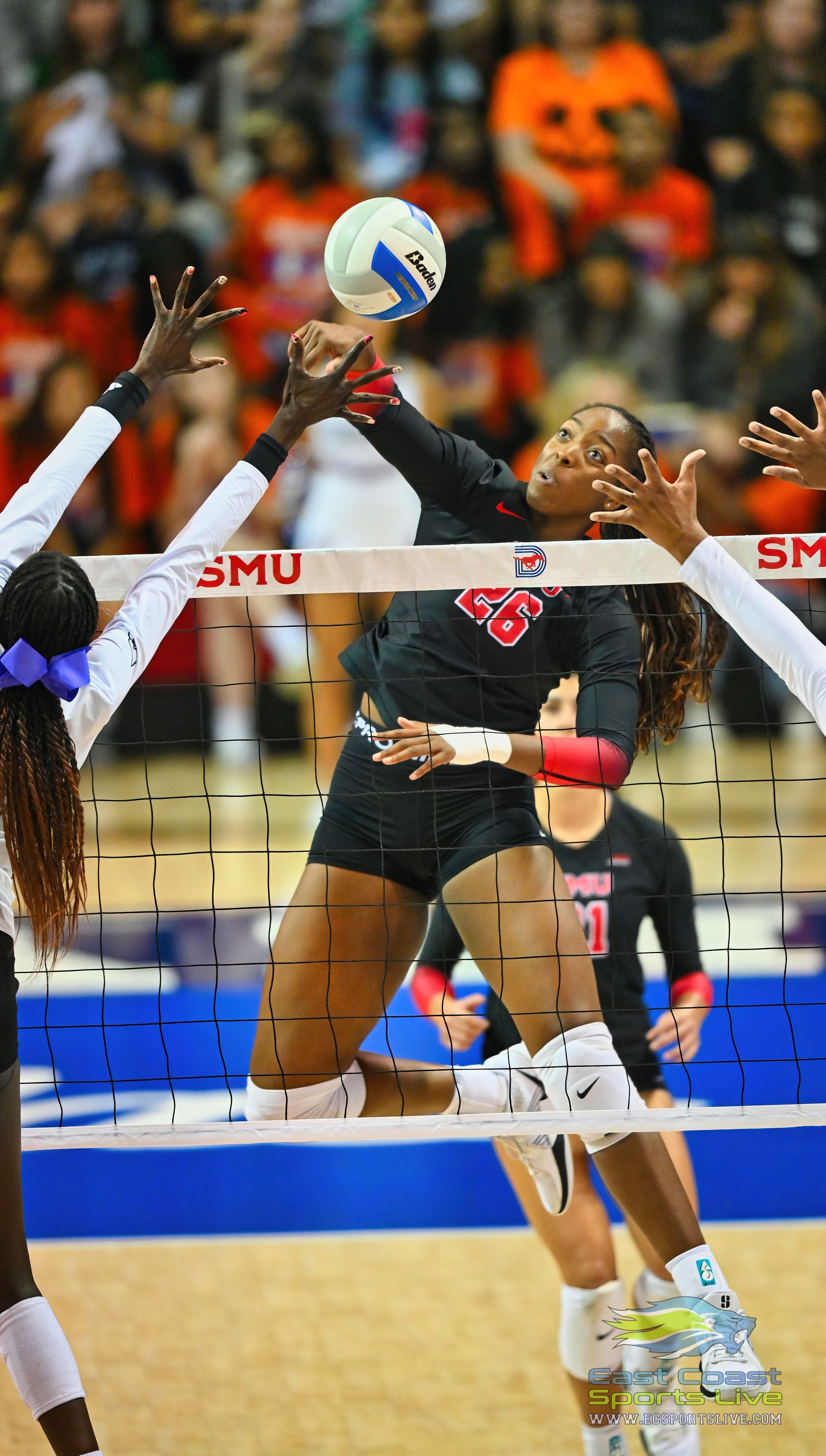 A woman is jumping to catch a volleyball in a volleyball game.