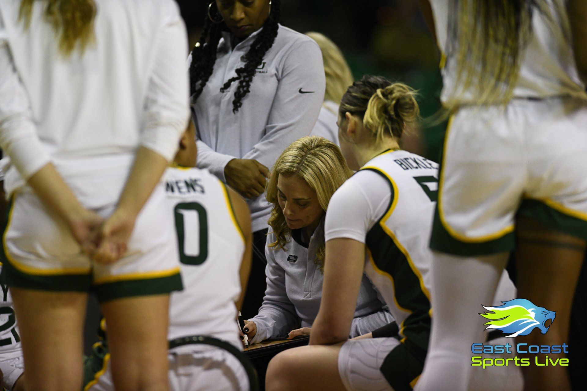 A group of female basketball players are huddled together and one of them has the number 0 on her jersey