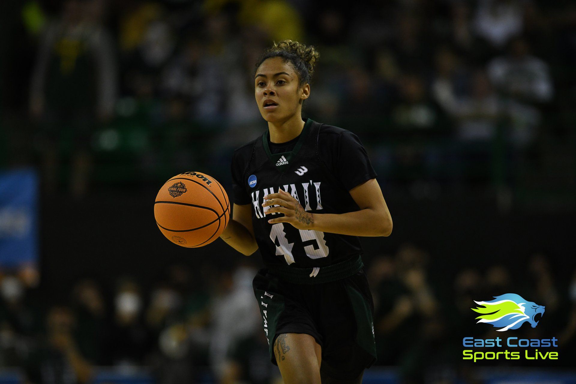 A female basketball player is dribbling the ball during a game.