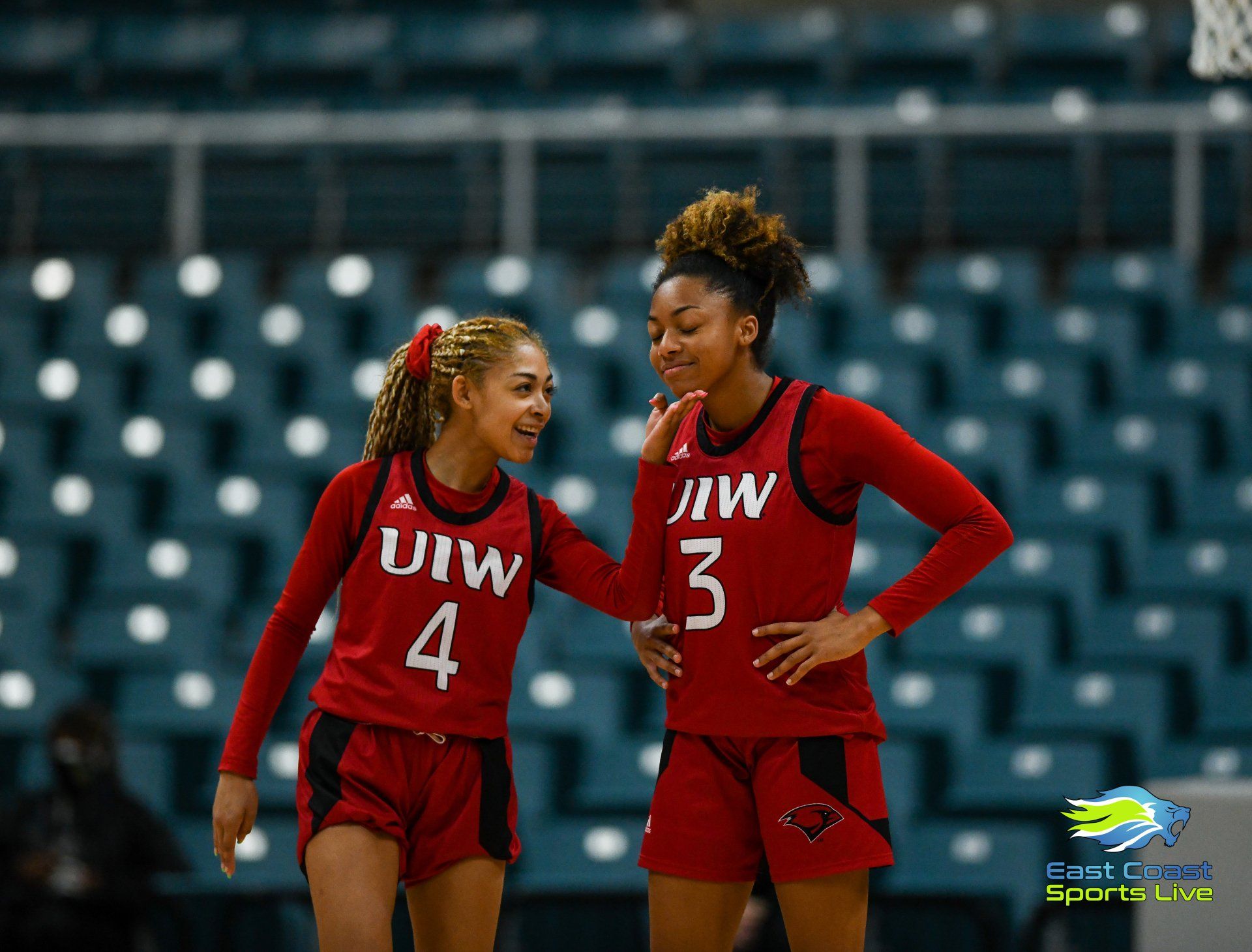 Two women are standing next to each other on a basketball court.