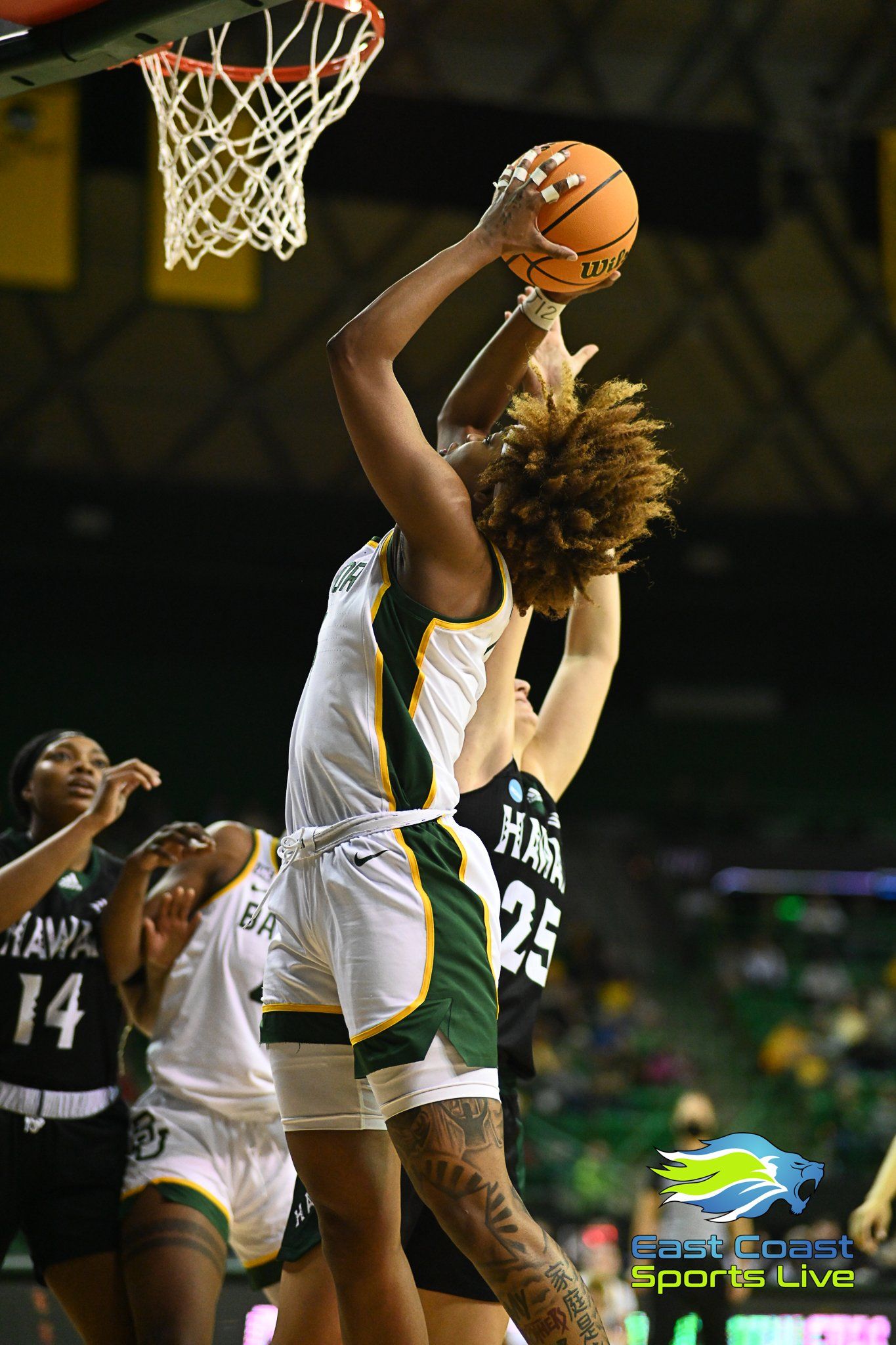 A female basketball player is jumping in the air to dunk the ball.