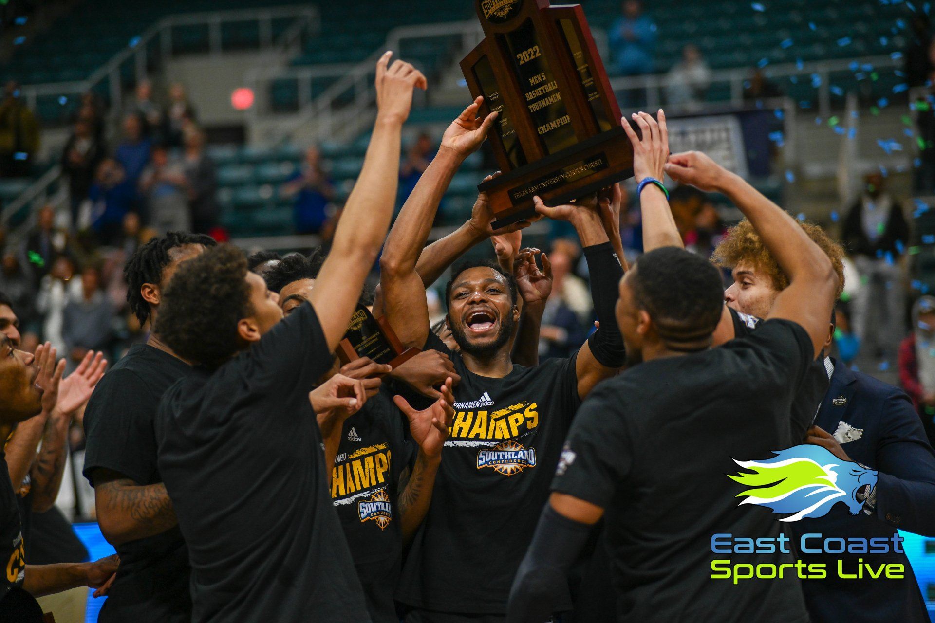 A group of basketball players are holding a trophy in the air.