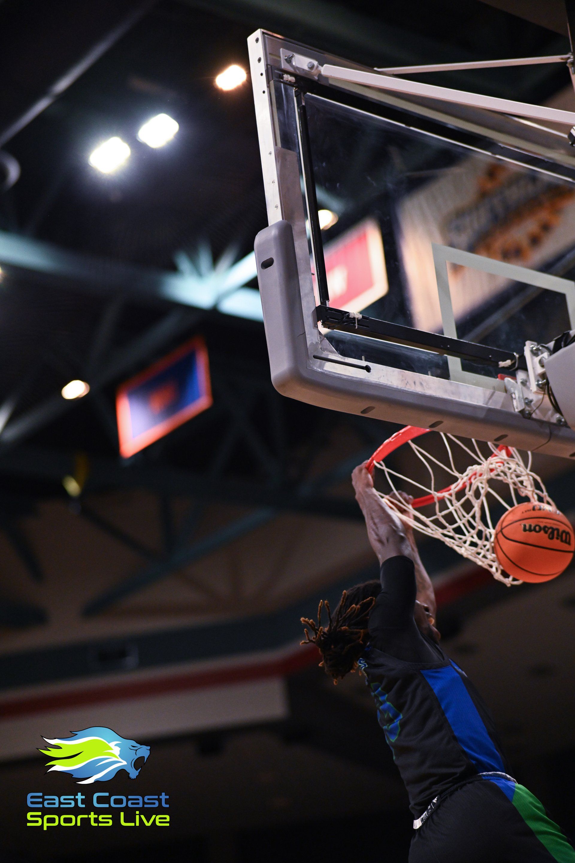 A basketball is going through the net during a game sponsored by east coast sports live