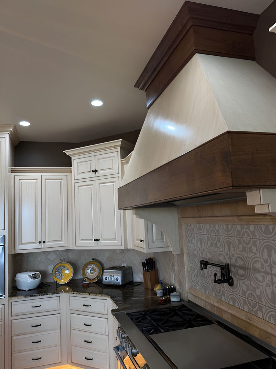 Kitchen with white cabinets, dark wood range hood, gas stove, and granite countertops