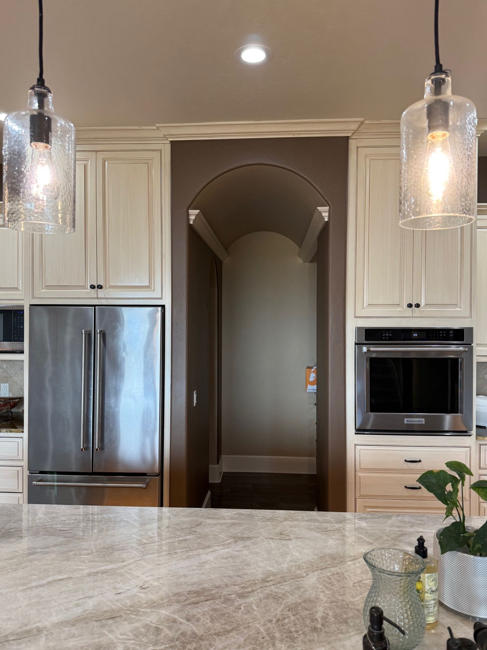 Modern kitchen with white cabinets, stainless steel fridge, built-in oven, and granite island counter.