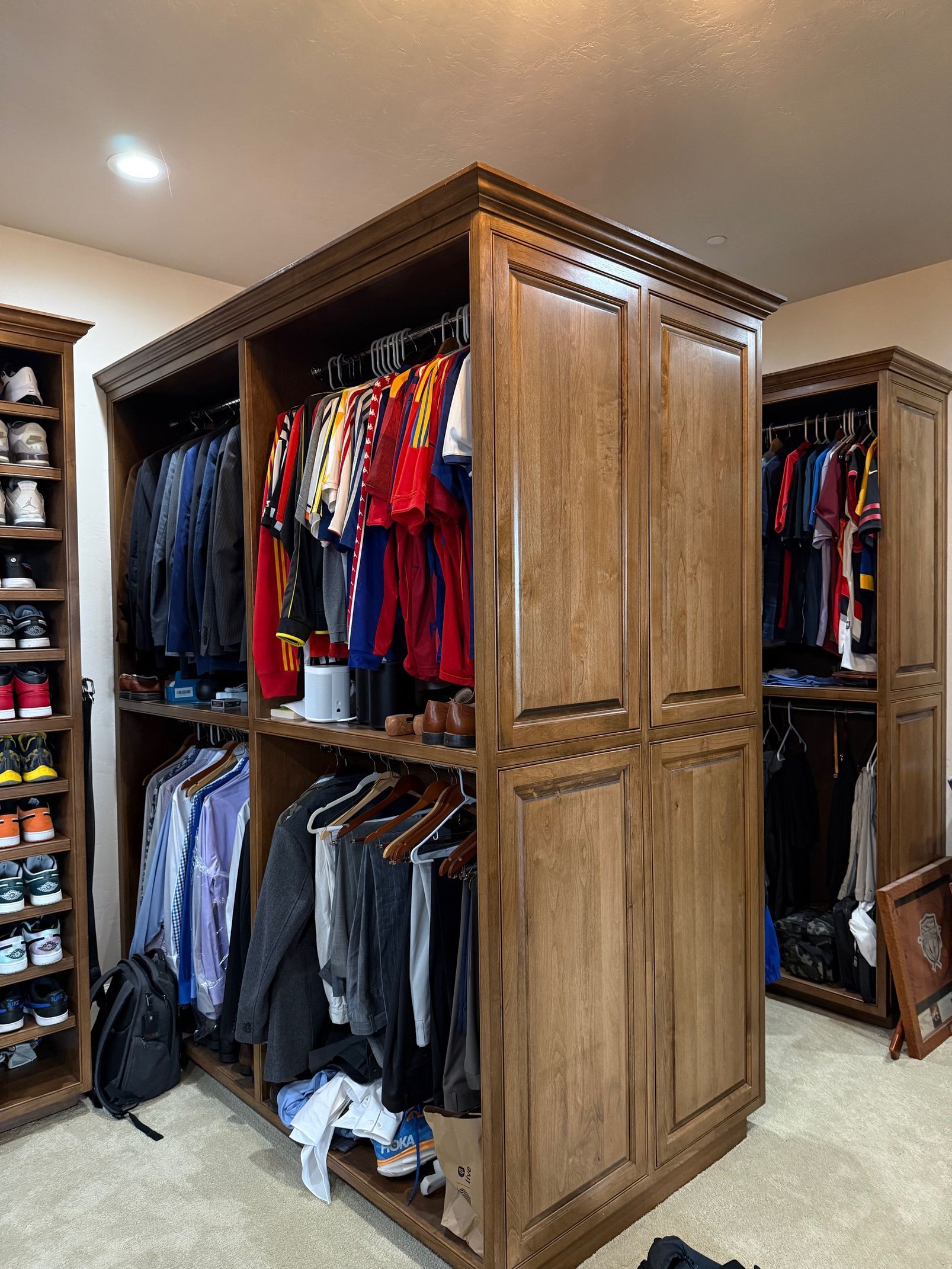 Wooden closet island with hanging clothes in a walk-in bedroom closet