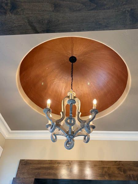 Copper-domed ceiling chandelier with three lit bulbs hanging in a room