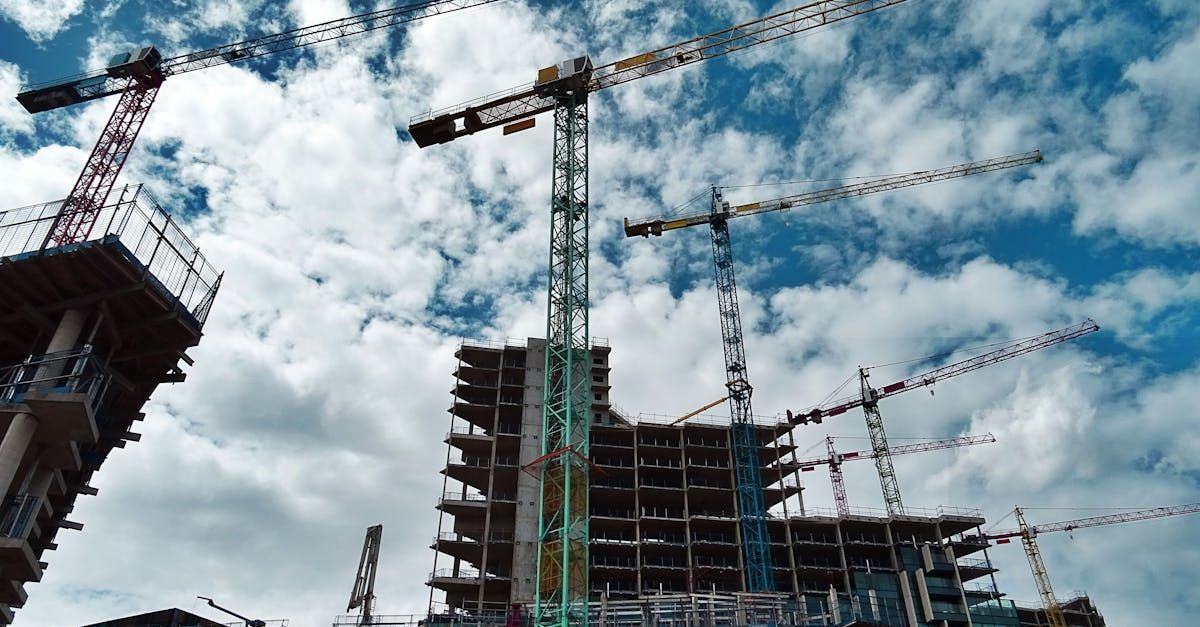 A building is being built with cranes and a blue sky in the background.