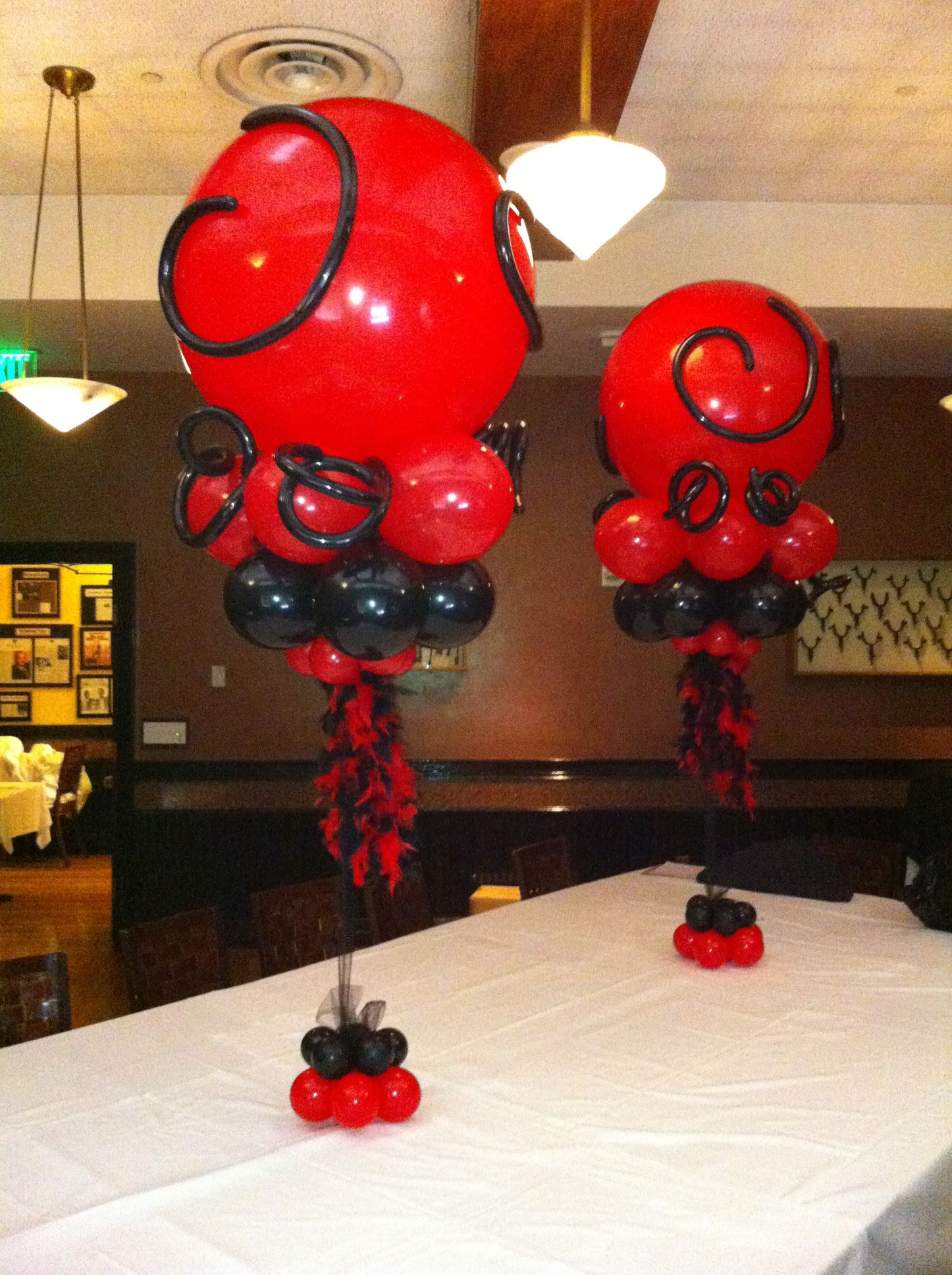 Two red and black balloons are sitting on a table