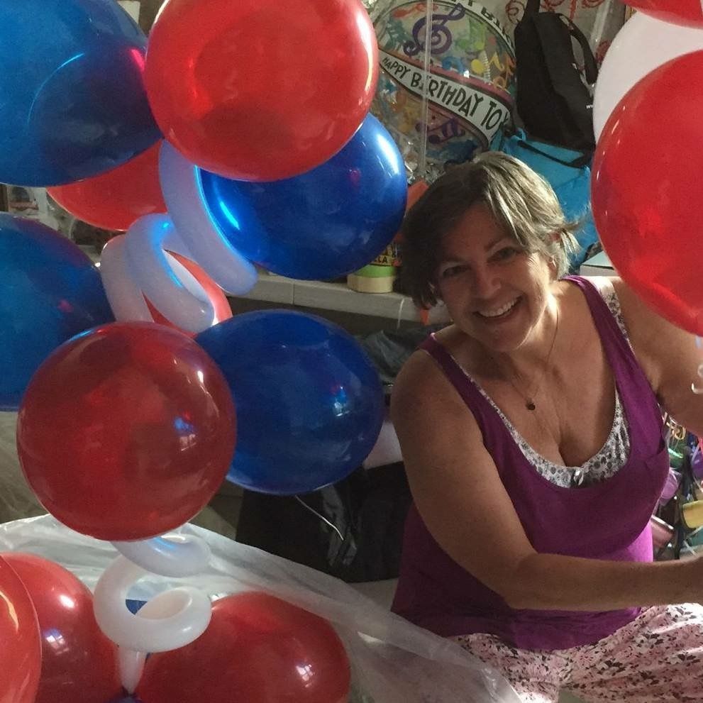 woman smiling next to red and blue balloons