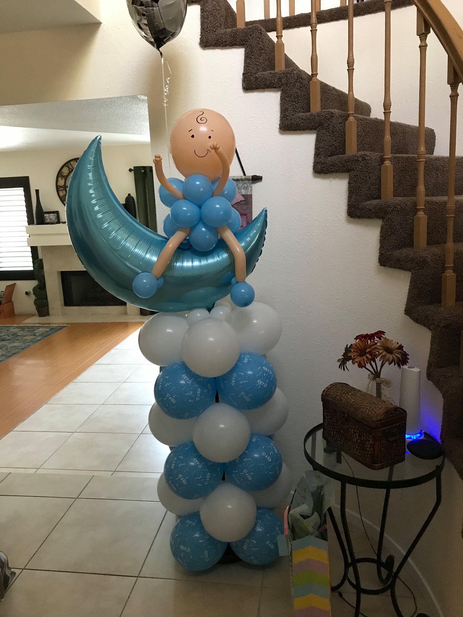 A baby is sitting on a crescent moon made of balloons.