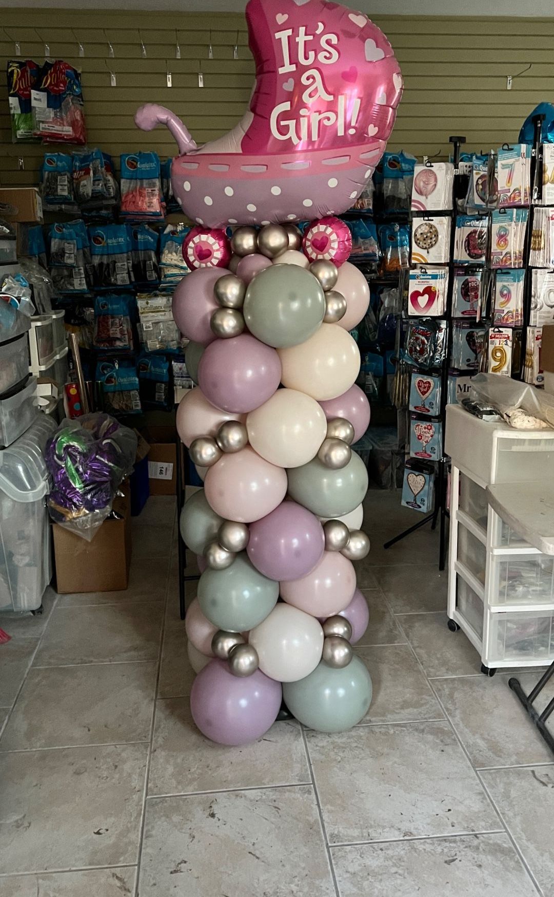 A column of balloons with a balloon in the middle that says `` it 's a girl ''.
