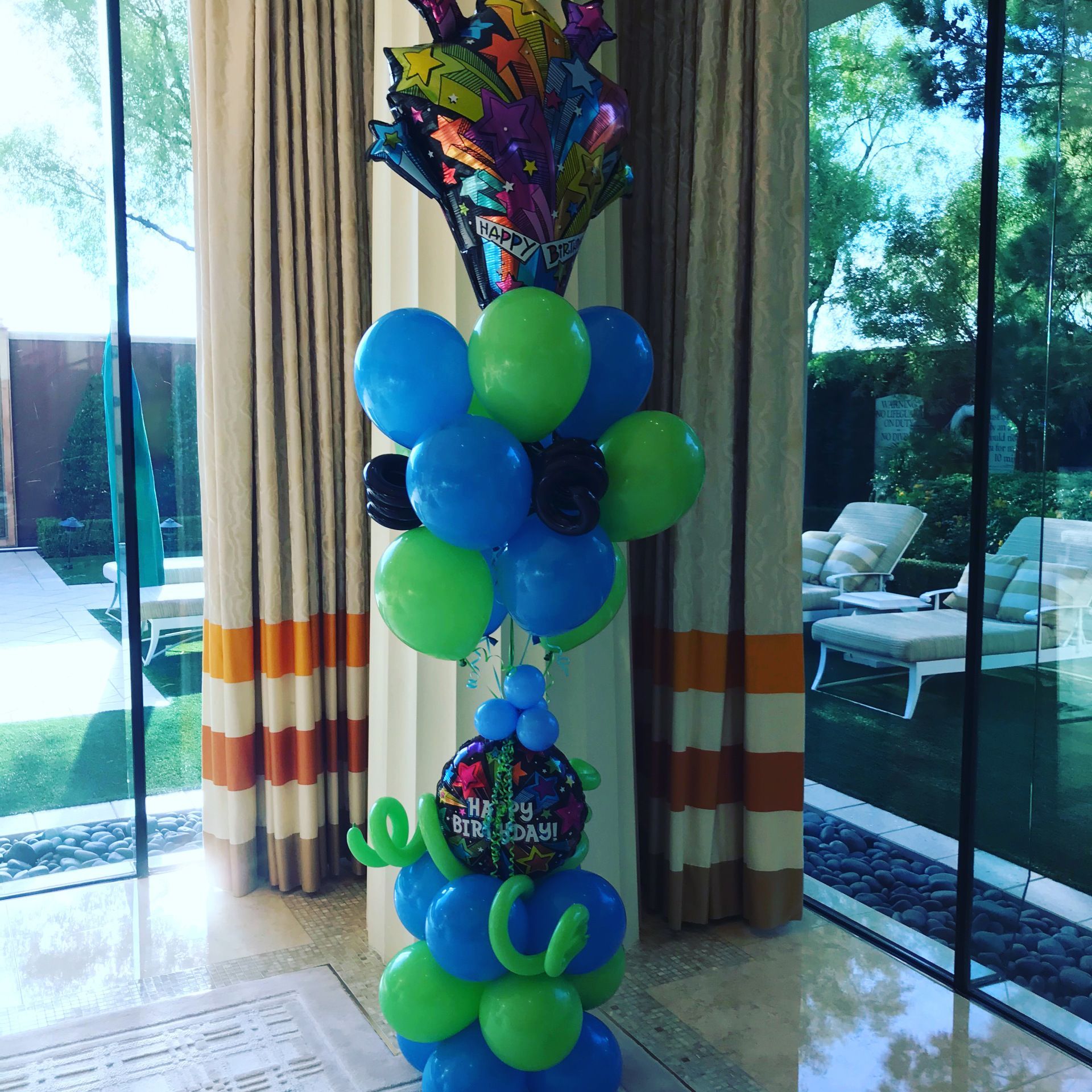A bunch of blue and green balloons are stacked on top of each other