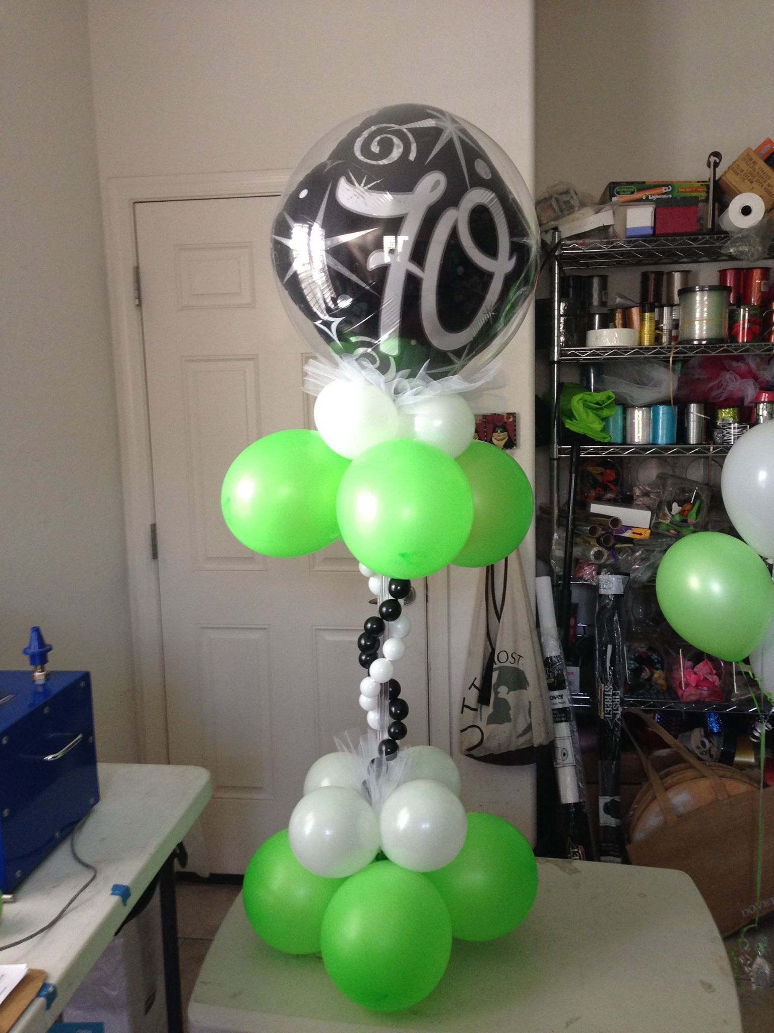 A balloon with the number 70 on it is surrounded by green and white balloons