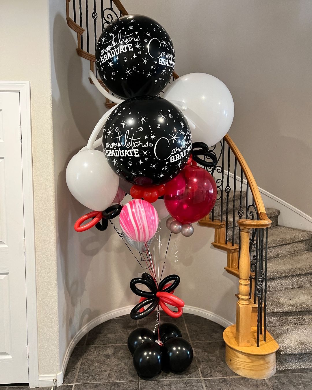 A bunch of balloons are sitting on the floor in front of a staircase.