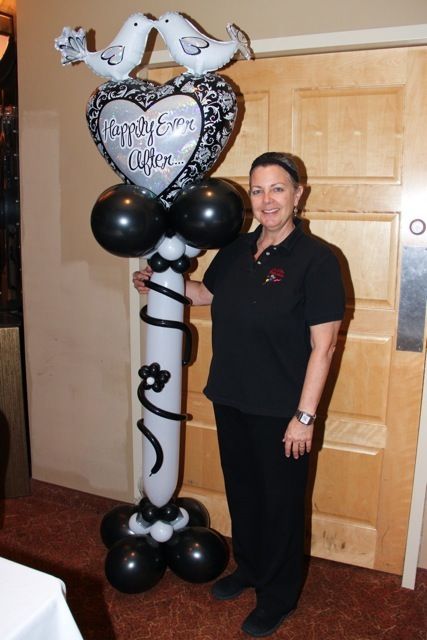 A woman is standing in front of a balloon display that says happily ever after