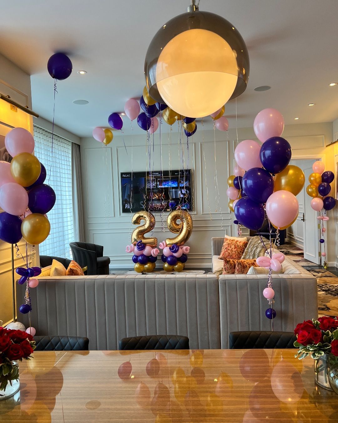 A living room decorated with balloons and flowers for a 29th birthday.