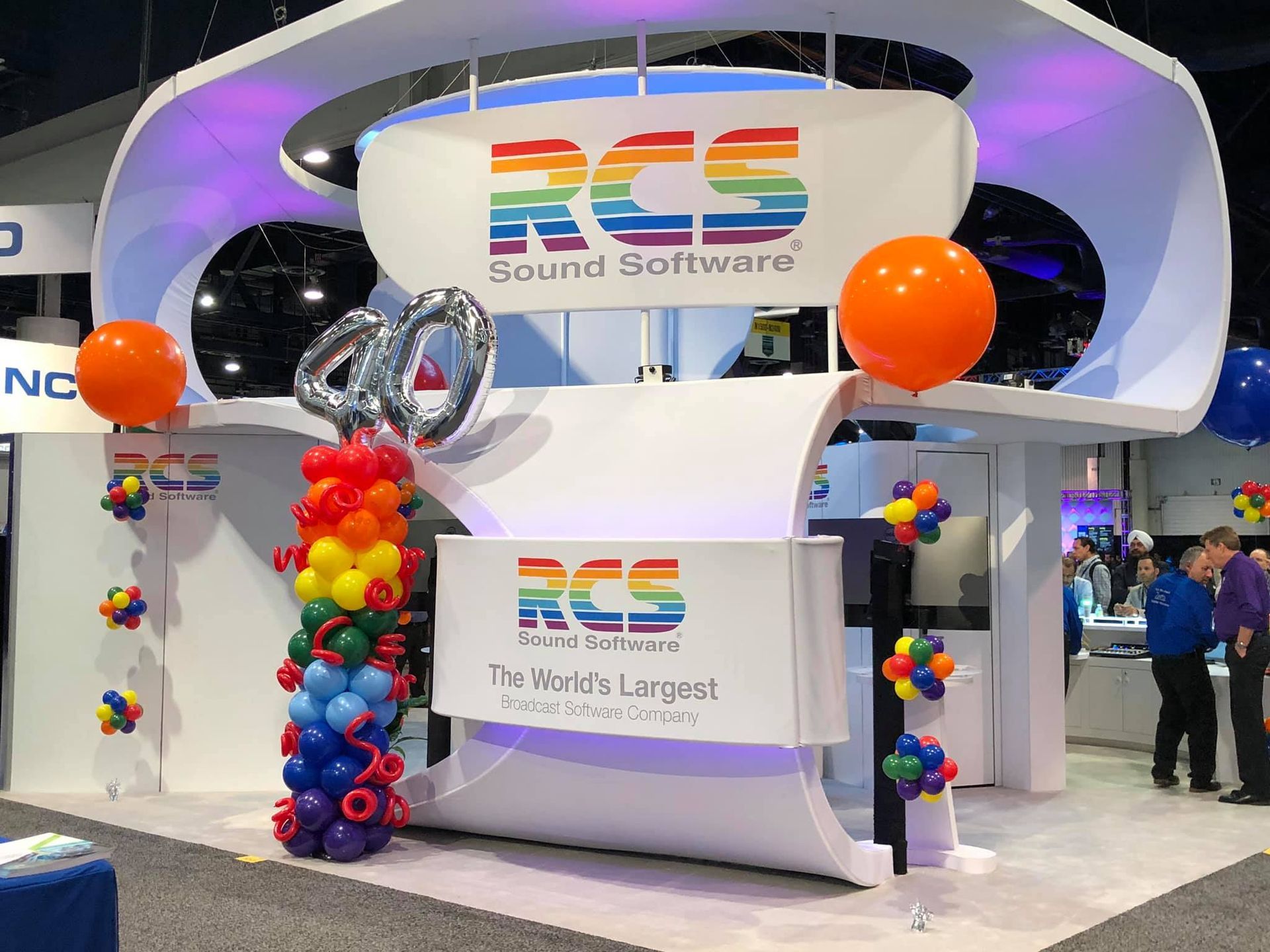 A booth for rcs sound software is decorated with balloons