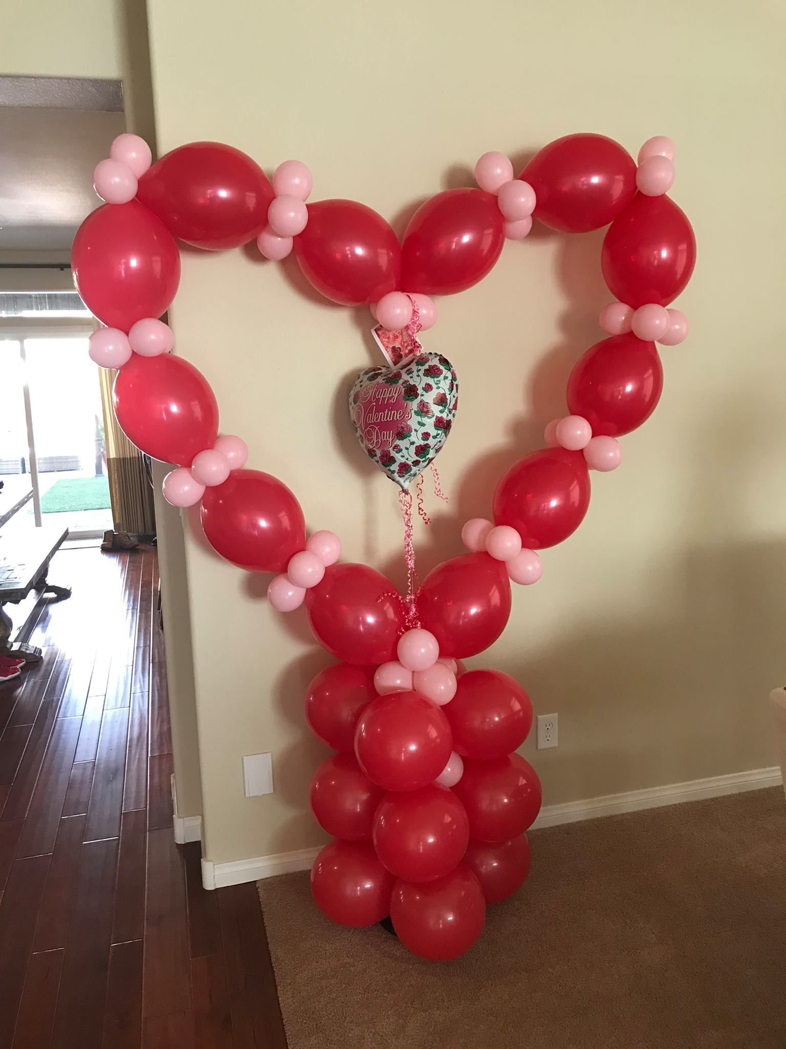 A heart made of red and pink balloons in a room