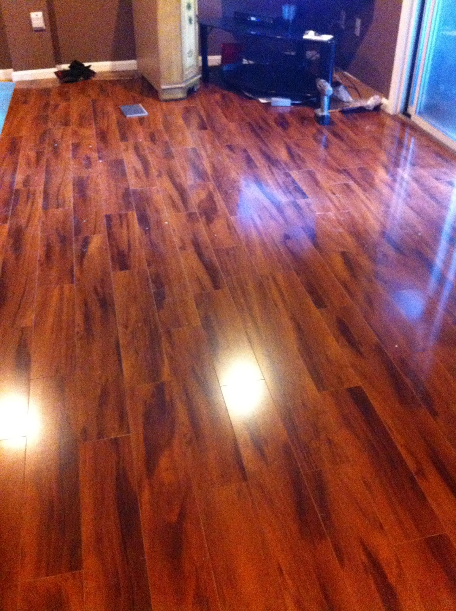 Shiny, brown wood laminate floor reflecting light in a room with a heater and entertainment center.