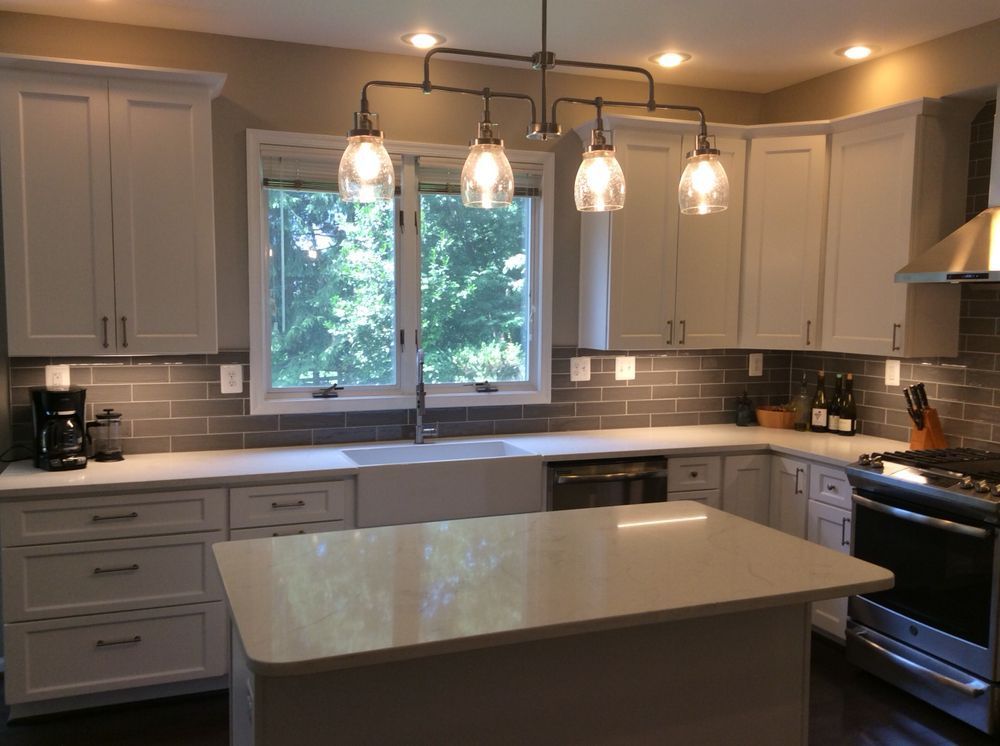 Modern kitchen with white cabinets, gray backsplash, and a white island.